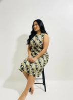 Woman in patterned sleeveless dress sitting on stool, ArokaLife contemporary fashion.